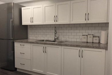 Inspiration for a mid-sized modern single-wall laminate floor and gray floor eat-in kitchen remodel in Calgary with a double-bowl sink, shaker cabinets, white cabinets, laminate countertops, white backsplash, subway tile backsplash, stainless steel appliances and no island