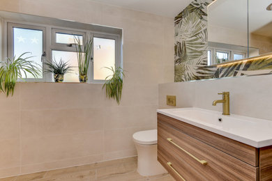 This is an example of a medium sized world-inspired ensuite bathroom in Sussex with flat-panel cabinets, medium wood cabinets, a walk-in shower, a two-piece toilet, beige tiles, ceramic tiles, beige walls, wood-effect flooring, a built-in sink, tiled worktops, brown floors, beige worktops, feature lighting, a single sink and a floating vanity unit.