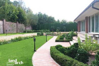 Ejemplo de jardín tradicional renovado en patio con muro de contención, exposición total al sol y adoquines de ladrillo