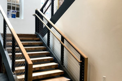 Foto de escalera en U ecléctica de tamaño medio sin contrahuella con escalones de madera, barandilla de cable y ladrillo