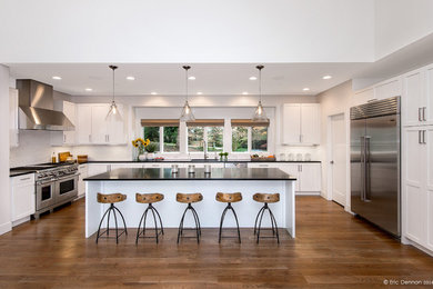 Photo of a large contemporary u-shaped eat-in kitchen in Seattle with medium hardwood floors, an undermount sink, shaker cabinets, white cabinets, granite benchtops, white splashback, subway tile splashback, stainless steel appliances and with island.