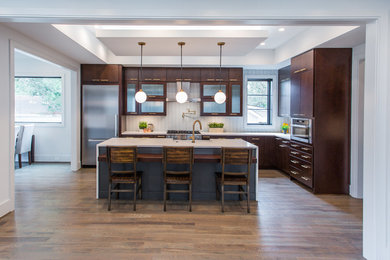 Inspiration for a large modern l-shaped eat-in kitchen in Charlotte with a farmhouse sink, flat-panel cabinets, dark wood cabinets, quartz benchtops, beige splashback, stainless steel appliances, medium hardwood floors, with island and brown floor.