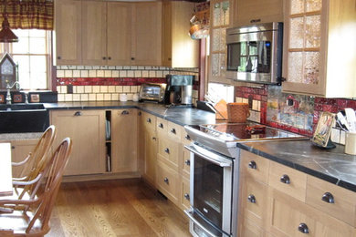 Large farmhouse l-shaped medium tone wood floor eat-in kitchen photo in Philadelphia with a farmhouse sink, shaker cabinets, light wood cabinets, soapstone countertops, red backsplash, ceramic backsplash and stainless steel appliances