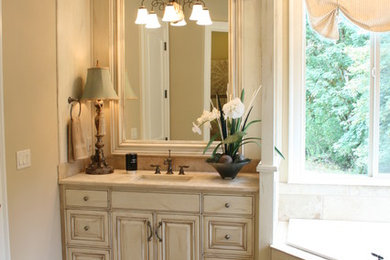 Example of a large classic master beige tile and white tile limestone floor bathroom design in Portland with raised-panel cabinets, distressed cabinets, a two-piece toilet, beige walls, an undermount sink and marble countertops