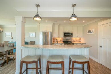 Inspiration for a mid-sized coastal galley light wood floor and beige floor open concept kitchen remodel in Other with shaker cabinets, white cabinets, granite countertops, multicolored backsplash, stainless steel appliances, an island and an undermount sink