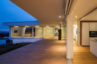 Photo of a large contemporary deck in Stuttgart with a roof extension.
