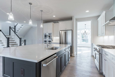 Huge l-shaped light wood floor open concept kitchen photo in DC Metro with an undermount sink, recessed-panel cabinets, quartz countertops, white backsplash, subway tile backsplash, stainless steel appliances, an island and multicolored countertops