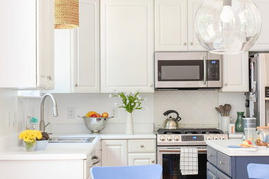 Inspiration for a mid-sized transitional l-shaped medium tone wood floor eat-in kitchen remodel in Nashville with a drop-in sink, raised-panel cabinets, white cabinets, laminate countertops, white backsplash, ceramic backsplash, stainless steel appliances, an island and white countertops