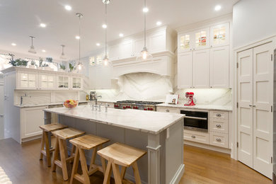Open concept kitchen - huge traditional u-shaped medium tone wood floor and brown floor open concept kitchen idea in Other with a farmhouse sink, shaker cabinets, white cabinets, quartz countertops, white backsplash, stone slab backsplash, stainless steel appliances and an island