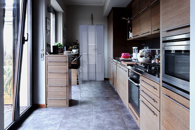 Idee per una cucina parallela minimal chiusa e di medie dimensioni con lavello da incasso, ante lisce, ante in legno bruno, top in acciaio inossidabile, paraspruzzi a specchio, elettrodomestici in acciaio inossidabile, pavimento in gres porcellanato e nessuna isola