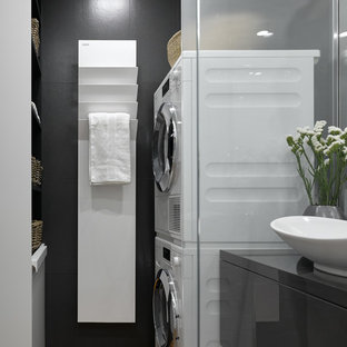 This is an example of a contemporary utility room in Moscow with black walls and a stacked washer and dryer.