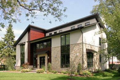 Large contemporary beige two-story stone house exterior idea in Chicago with a shed roof, a shingle roof and a brown roof