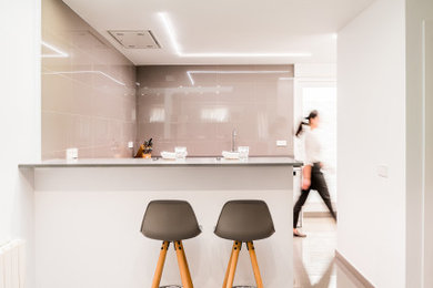 Modelo de cocinas en U contemporáneo de tamaño medio abierto con fregadero bajoencimera, armarios con paneles lisos, puertas de armario blancas, encimera de cuarzo compacto, salpicadero verde, salpicadero de azulejos de porcelana, electrodomésticos blancos, suelo de baldosas de porcelana, península, suelo gris y encimeras grises