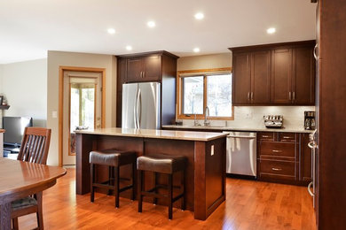Inspiration for a large modern u-shaped light wood floor eat-in kitchen remodel in Orange County with a double-bowl sink, flat-panel cabinets, dark wood cabinets, granite countertops, white backsplash, ceramic backsplash, stainless steel appliances and an island