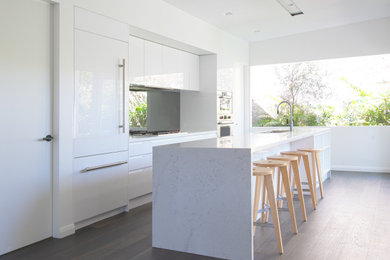 Inspiration for a mid-sized modern single-wall separate kitchen in Sydney with an undermount sink, flat-panel cabinets, white cabinets, marble benchtops, mirror splashback, stainless steel appliances, dark hardwood floors, with island, brown floor and white benchtop.