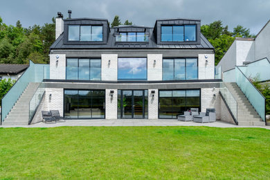 Inspiration for a large contemporary white three-story brick exterior home remodel in Other with a metal roof and a black roof