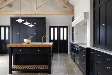 This is an example of a transitional kitchen in Cheshire with a farmhouse sink, black cabinets, quartzite benchtops, with island and white benchtop.