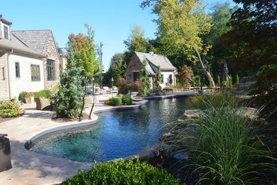Inspiration for a large country backyard custom-shaped pool in St Louis with a water feature and natural stone pavers.