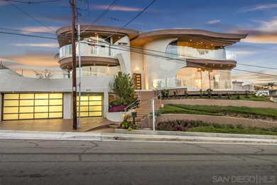 Example of a large trendy beige two-story stone exterior home design in San Diego with a mixed material roof