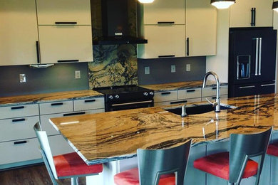 Mid-sized trendy single-wall medium tone wood floor and brown floor eat-in kitchen photo in Other with an undermount sink, flat-panel cabinets, white cabinets, granite countertops, gray backsplash, stone slab backsplash, black appliances and an island