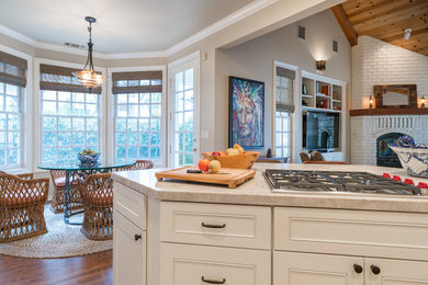 Large arts and crafts l-shaped medium tone wood floor and brown floor eat-in kitchen photo in Other with a farmhouse sink, shaker cabinets, white cabinets, granite countertops, white backsplash, subway tile backsplash, stainless steel appliances, an island and gray countertops