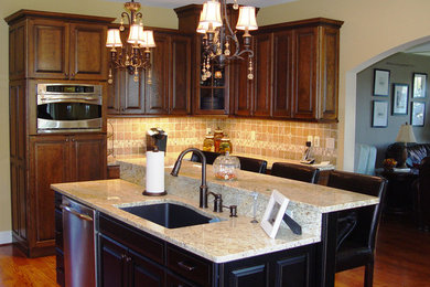 Inspiration for a mid-sized craftsman u-shaped medium tone wood floor and brown floor eat-in kitchen remodel in Bridgeport with a single-bowl sink, dark wood cabinets, granite countertops, beige backsplash, mosaic tile backsplash, stainless steel appliances, an island and raised-panel cabinets