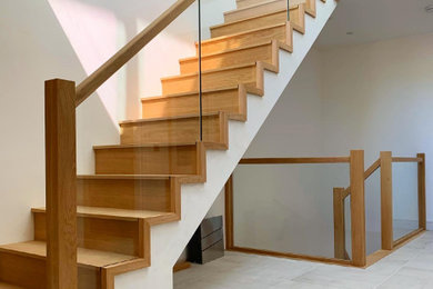 Foto de escalera moderna de tamaño medio con escalones de madera, contrahuellas de madera y barandilla de vidrio