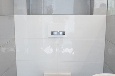 Inspiration for a small modern 3/4 gray tile and ceramic tile ceramic tile bathroom remodel in Other with a wall-mount sink, flat-panel cabinets, white cabinets, laminate countertops, a wall-mount toilet and white walls