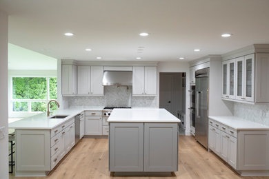 デトロイトにある高級な広いトランジショナルスタイルのおしゃれなキッチン (ドロップインシンク、シェーカースタイル扉のキャビネット、グレーのキャビネット、クオーツストーンカウンター、白いキッチンパネル、大理石のキッチンパネル、シルバーの調理設備、淡色無垢フローリング、ベージュの床、白いキッチンカウンター) の写真