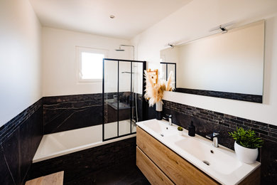 Idées déco pour une salle de bain grise et noire contemporaine en bois clair de taille moyenne pour enfant avec un placard à porte plane, une baignoire encastrée, un combiné douche/baignoire, un carrelage noir, des carreaux de béton, un mur noir, carreaux de ciment au sol, un lavabo encastré, un plan de toilette en quartz modifié, un sol noir, une cabine de douche à porte battante, un plan de toilette noir, meuble double vasque et meuble-lavabo suspendu.
