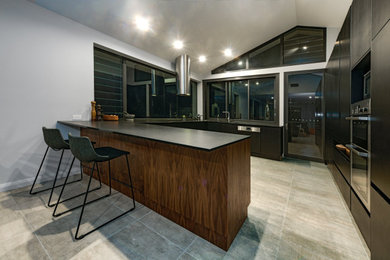 This is an example of a large modern u-shaped eat-in kitchen in Newcastle - Maitland with an undermount sink, flat-panel cabinets, black cabinets, laminate benchtops, stainless steel appliances, no island, black benchtop and vaulted.