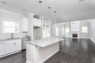 Example of a mid-sized classic l-shaped dark wood floor and brown floor open concept kitchen design in Other with an undermount sink, shaker cabinets, white cabinets, granite countertops, white backsplash, subway tile backsplash, an island and gray countertops