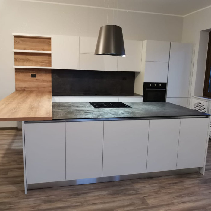 Cucina con anta Rovere Bianco e maniglia a Gola Inox. Un'isola con doppie basi per avere molto spazio a disposizione. Top in HPL Pietra Grey da 1cm con vasca integrata e schienale. Un piano da 4cm fin