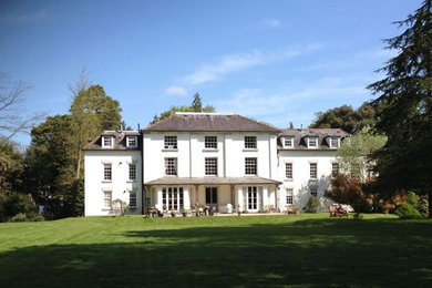 Foto de fachada de casa blanca y gris clásica grande de tres plantas con revestimiento de estuco, tejado a dos aguas y tejado de teja de barro