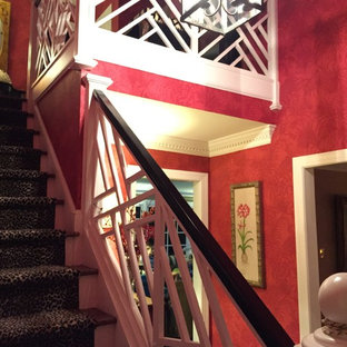 Inredning av en eklektisk liten foajé, med röda väggar, mellanmörkt trägolv, en enkeldörr och en blå dörr