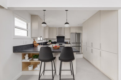 Example of a mid-sized trendy ceramic tile and gray floor eat-in kitchen design in Vancouver with an undermount sink, flat-panel cabinets, quartz countertops, black backsplash, quartz backsplash, stainless steel appliances, an island and black countertops