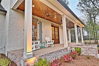 This is an example of a mid-sized farmhouse brick front porch design in Jackson with a roof extension.