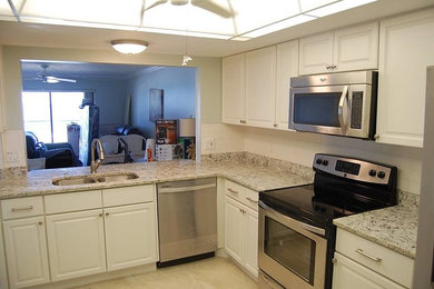 Photo of a mid-sized traditional kitchen in Orlando with a double-bowl sink, raised-panel cabinets, white cabinets, granite benchtops, white splashback, subway tile splashback, stainless steel appliances and no island.
