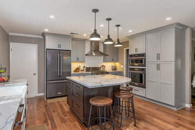 This is an example of a mid-sized traditional single-wall separate kitchen in San Francisco with a farmhouse sink, shaker cabinets, grey cabinets, granite benchtops, white splashback, subway tile splashback, stainless steel appliances, dark hardwood floors, with island, brown floor and grey benchtop.