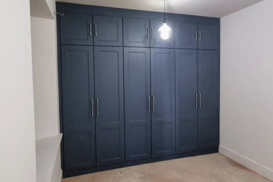 Modelo de armario y vestidor unisex clásico pequeño con a medida, armarios estilo shaker, puertas de armario azules, moqueta y suelo beige