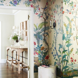 Eklektisk inredning av en stor foajé, med flerfärgade väggar, mörkt trägolv, en enkeldörr och en vit dörr