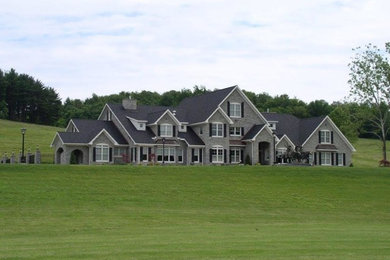 Example of a huge classic gray three-story stone gable roof design in Other
