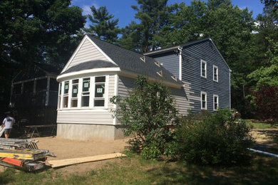 Foto de fachada de casa azul y negra de estilo americano de una planta con revestimiento de madera, tejado a dos aguas, tejado de teja de madera y tablilla