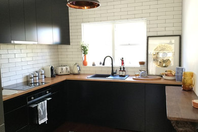 シドニーにある低価格の小さなインダストリアルスタイルのおしゃれなキッチン (ドロップインシンク、フラットパネル扉のキャビネット、木材カウンター、白いキッチンパネル、シルバーの調理設備、無垢フローリング、アイランドなし、黒いキャビネット、サブウェイタイルのキッチンパネル) の写真