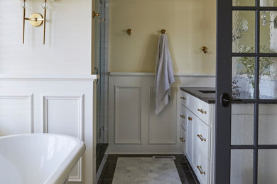 Bathroom - traditional master white tile and ceramic tile marble floor, white floor, double-sink and wainscoting bathroom idea in Chicago with recessed-panel cabinets, white cabinets, a two-piece toilet, yellow walls, an undermount sink, limestone countertops, a hinged shower door, gray countertops and a built-in vanity