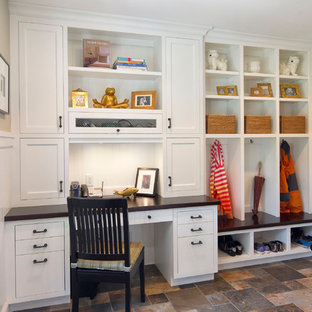 ニューヨークのトラディショナルスタイルのおしゃれな家事室 (スレートの床、フラットパネル扉のキャビネット、白いキャビネット、木材カウンター、ベージュの壁、黒いキッチンカウンター) の写真