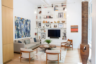 Example of a large trendy formal and enclosed light wood floor and beige floor living room design in New York with white walls, no fireplace and a wall-mounted tv