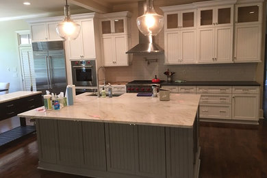 This is an example of a large classic u-shaped kitchen/diner in Atlanta with a belfast sink, shaker cabinets, white cabinets, granite worktops, white splashback, metro tiled splashback, stainless steel appliances, dark hardwood flooring and multiple islands.