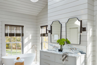 Example of a large beach style master white tile marble floor, white floor, double-sink, shiplap ceiling and shiplap wall bathroom design in New York with recessed-panel cabinets, white cabinets, white walls, an undermount sink, marble countertops, a hinged shower door, white countertops, a niche and a floating vanity