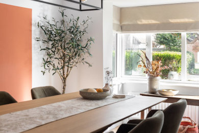 Design ideas for a medium sized eclectic enclosed dining room in Buckinghamshire with orange walls, no fireplace, laminate floors, beige floors and feature lighting.